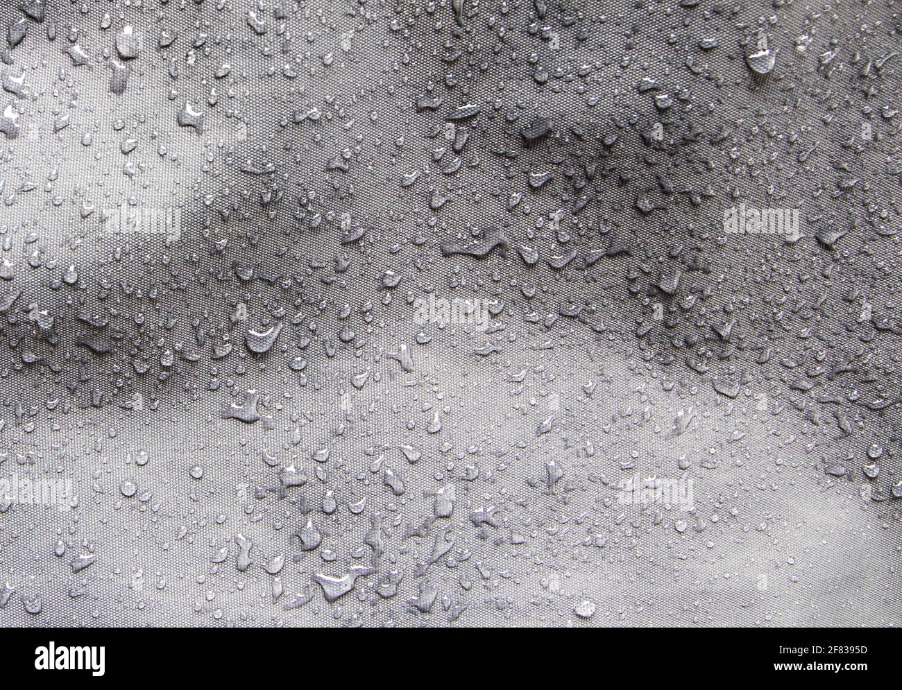 Wasserdichtes graues Nylongewebe, das nach Regen mit Wassertropfen bedeckt ist Stockfoto