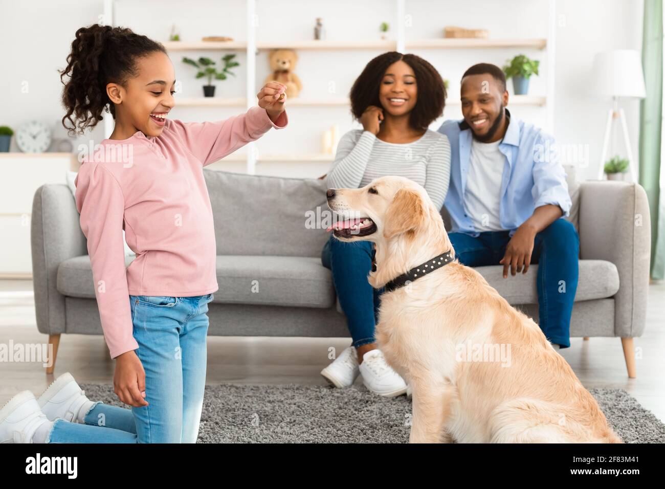 Schwarzes Mädchen, das ihrem gehorsamen Hund eine Freude macht Stockfoto