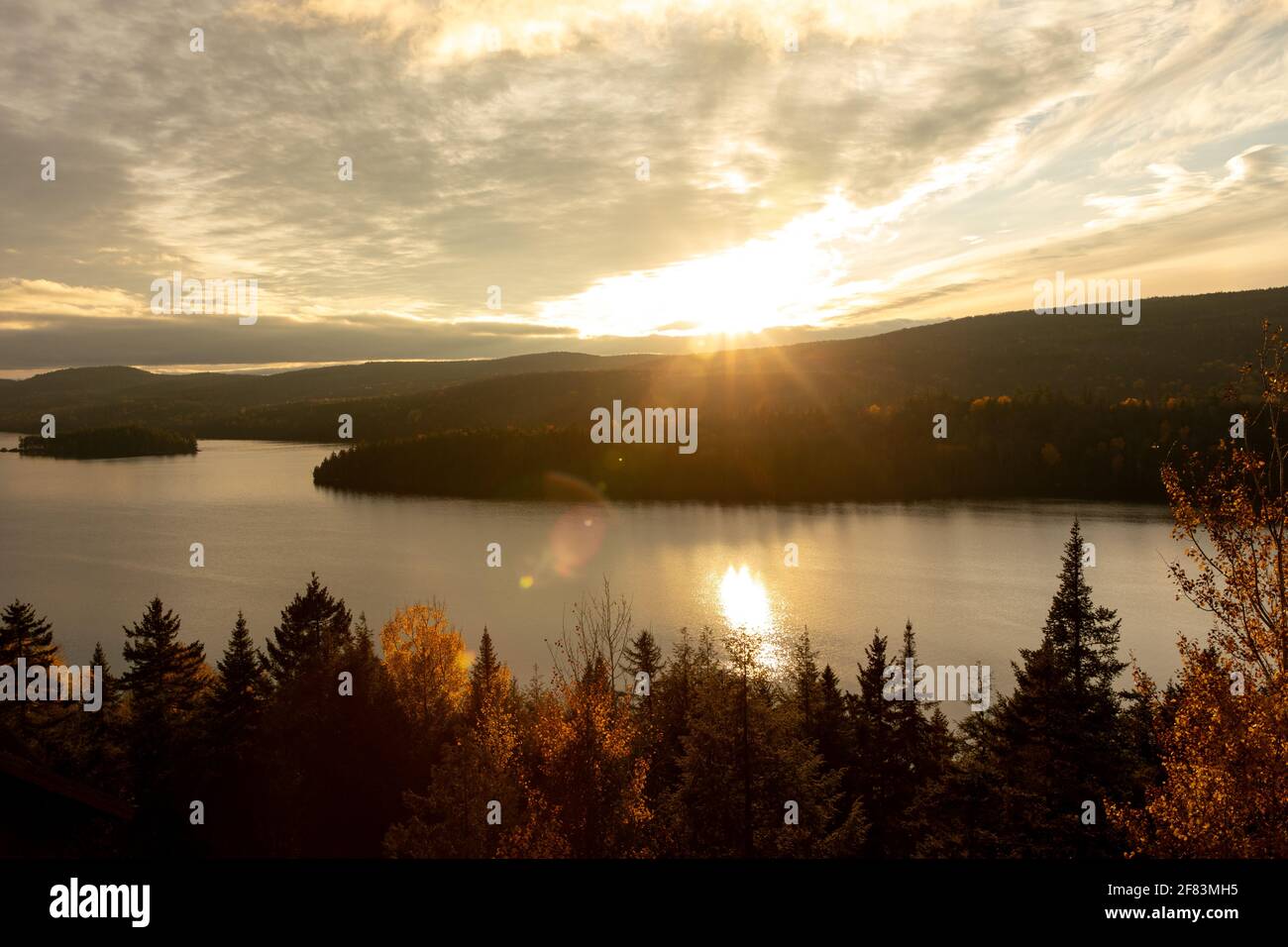Blick auf einen See bei Sonnenuntergang mit hellem Gelb Sonnenstrahlen Stockfoto