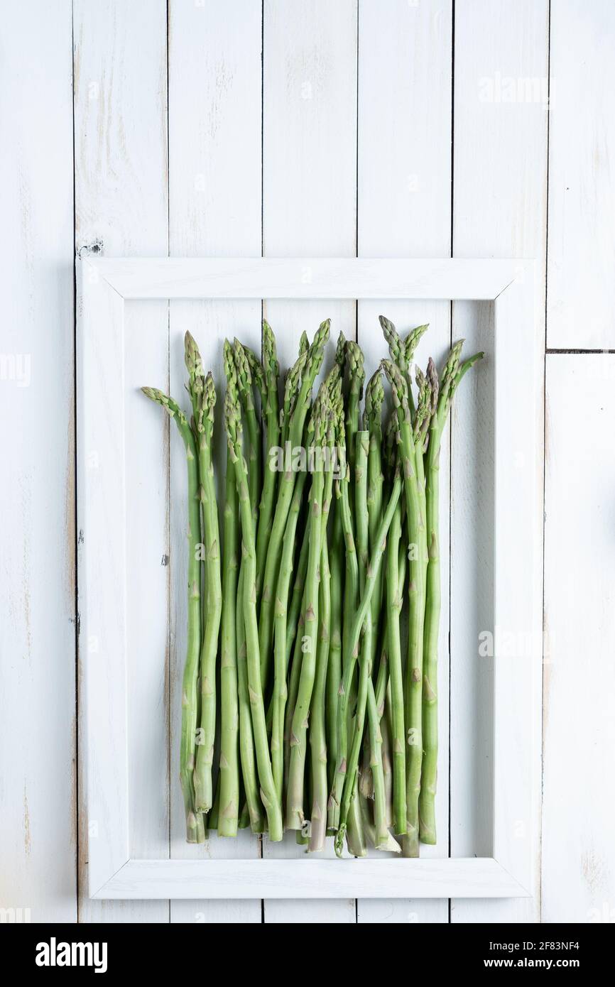 Der Spargel in einem Rahmen auf einem weißen alten Holz Platine Stockfoto