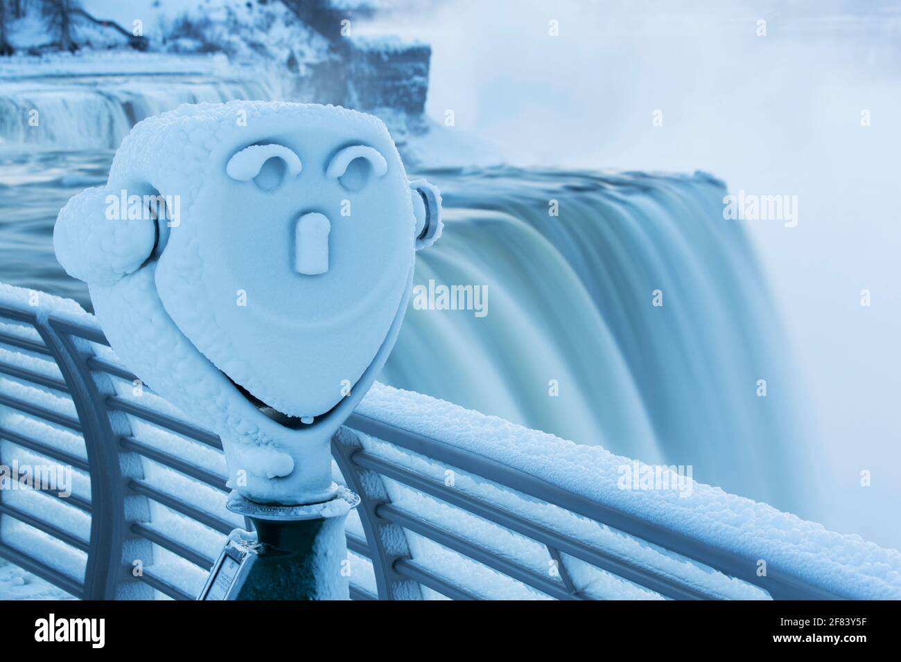 USA, New York, Niagarafälle, ein gefrorenes Teleskop, das im Winter wie ein Gesicht mit den amerikanischen Fällen im Hintergrund aussieht. Stockfoto