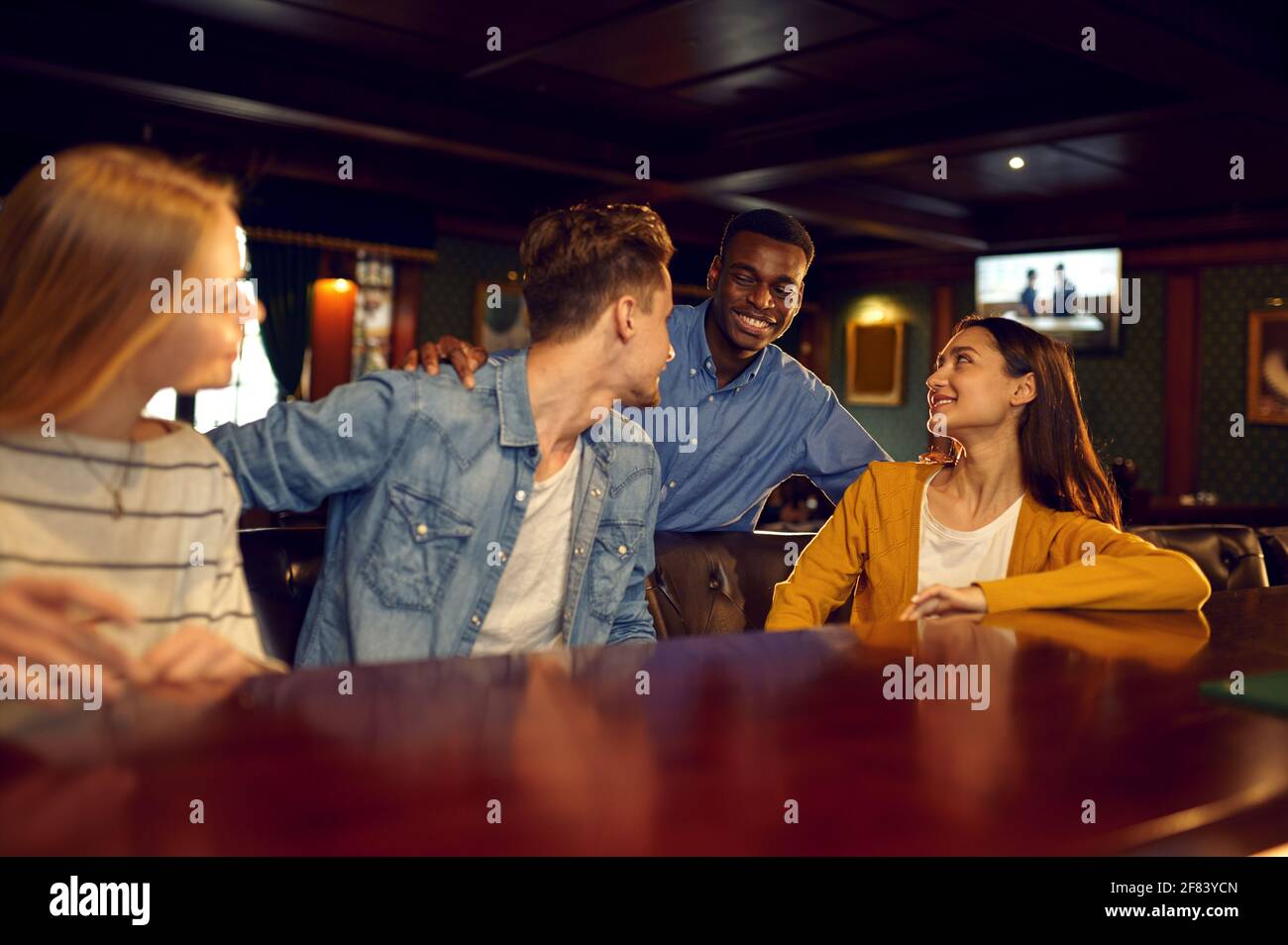 Lächelnde Freunde lassen sich an der Theke in der Bar ausklingen Stockfoto