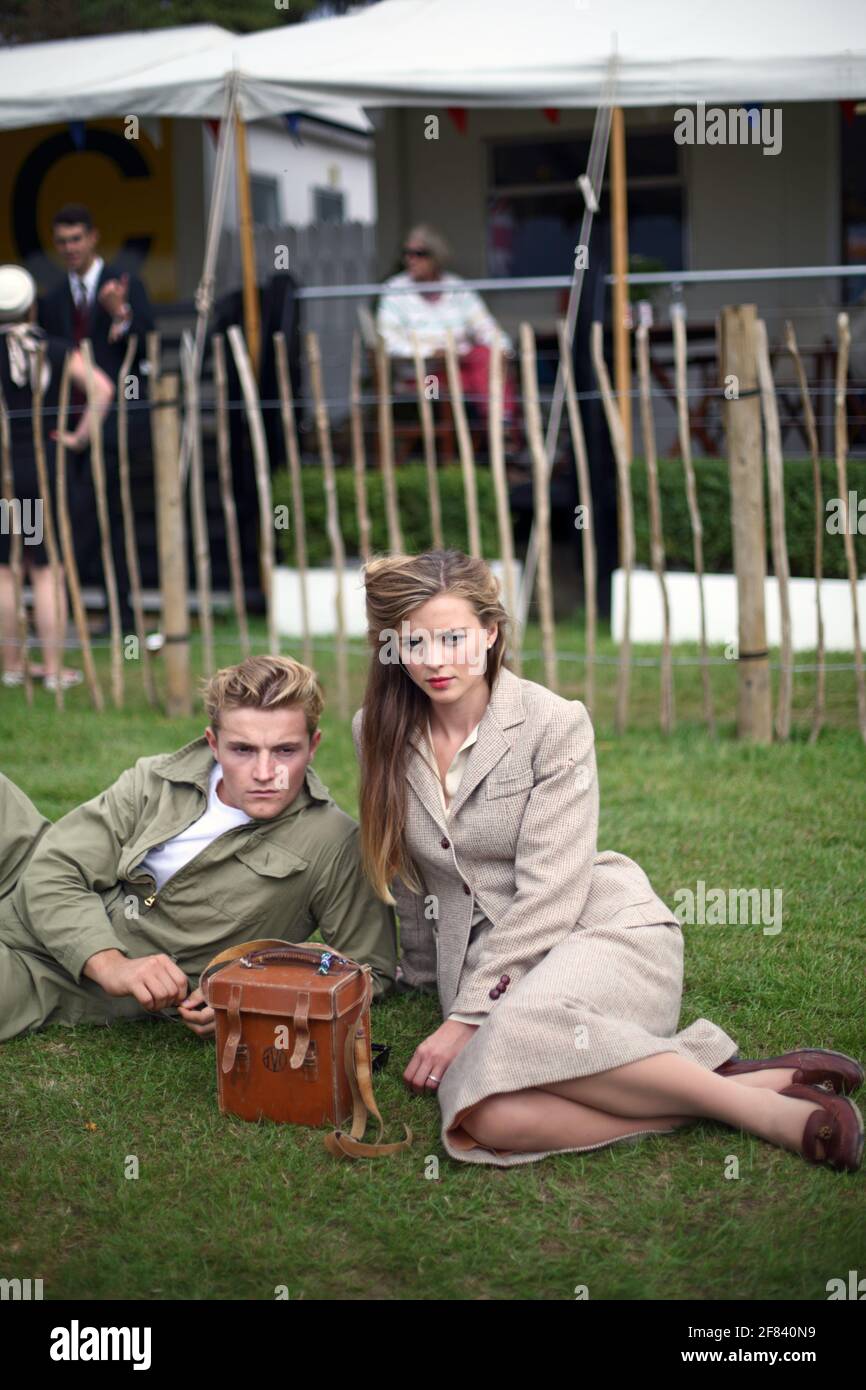Das Paar aus der Kriegszeit sitzt auf dem Rasen im Goodwood Revival, Großbritannien Stockfoto