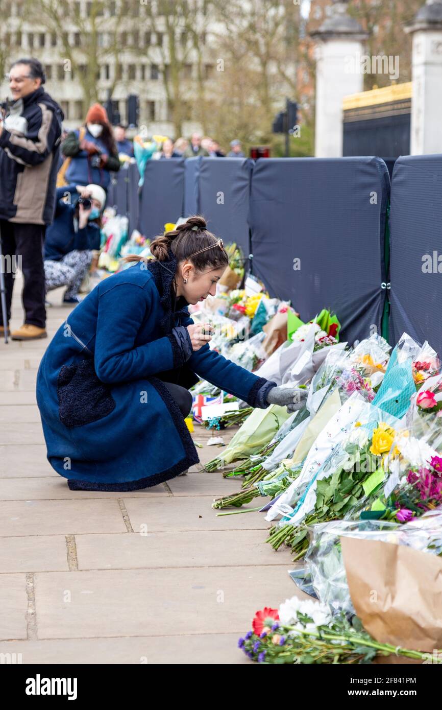 11. April 2021, London, Großbritannien - Frau, die nach seinem Tod am 9. April vor dem Buckingham Palace Blumen als Hommage an Prinz Philip, Herzog von Edinburgh, legt Stockfoto