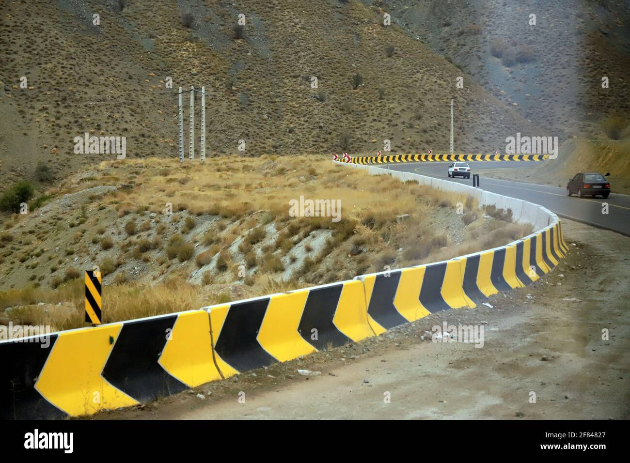 Iran auf der Strecke von Bam nach Mahan befindet sich diese gelb-schwarze Leitplanke Stockfoto