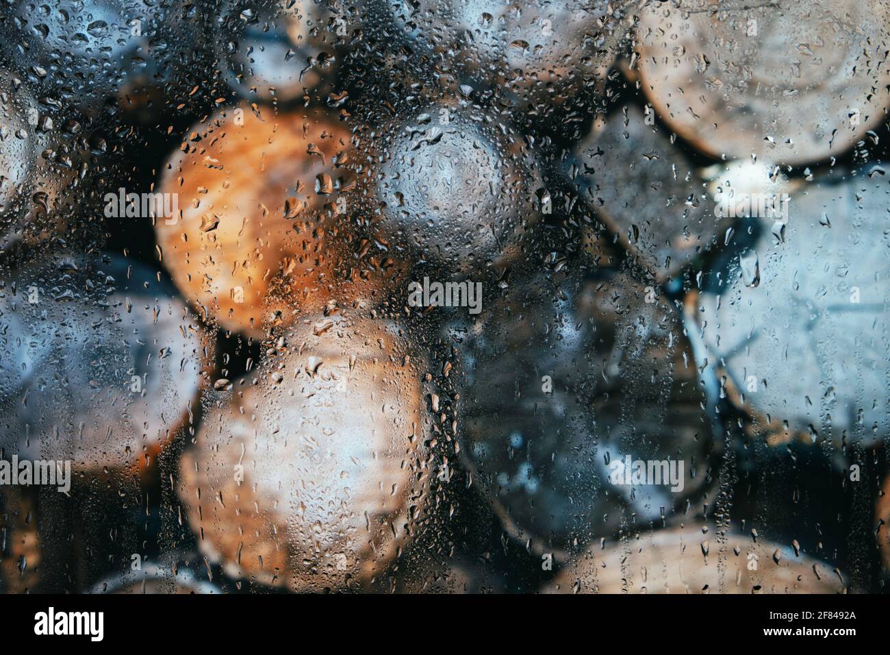 Glas nach Regen in Tropfen auf einem verschwommenen Hintergrund aus Rundholz Stockfoto