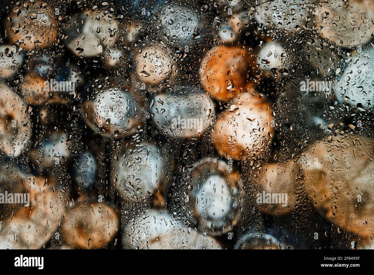 Glas nach Regen in Tropfen auf einem verschwommenen Hintergrund aus Rundholz Stockfoto