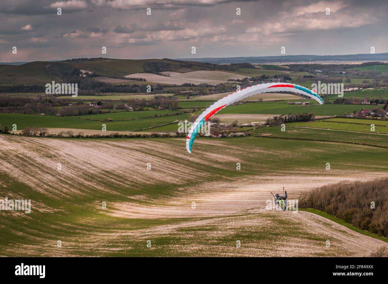 Firle, Lewes, East Sussex, Großbritannien. April 2021. Gleitschirmfliegen von den wunderschönen South Downs im kalten Nordwind wurde durch Squalls und gelegentliche Schneegüter unterbr... Es wird eine kalte Nacht mit der Möglichkeit von Schneeverwehungen morgen vorhergesagt. Kredit: David Burr/Alamy Live Nachrichten Stockfoto