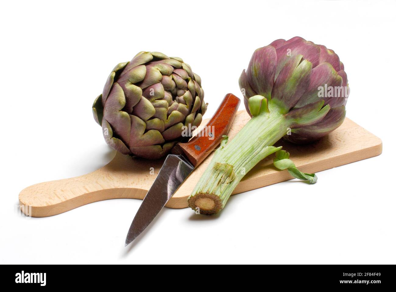 Artischocken (Cynara scolymus Cynara cardunculus) auf Schneidebrett mit Messer (Cynara scolymus, Cynara cardunculus) Stockfoto