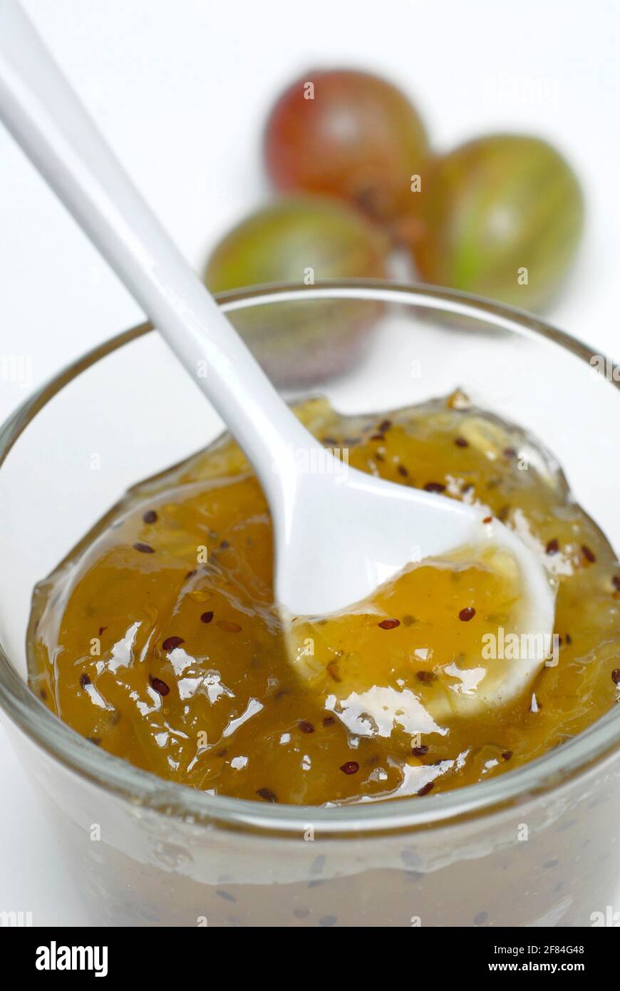 Glas Stachelbeermarmelade und Stachelbeeren (Ribes uva-Crispa), Stachelbeermarmelade, Marmelade, Marmelade, Löffel Stockfoto