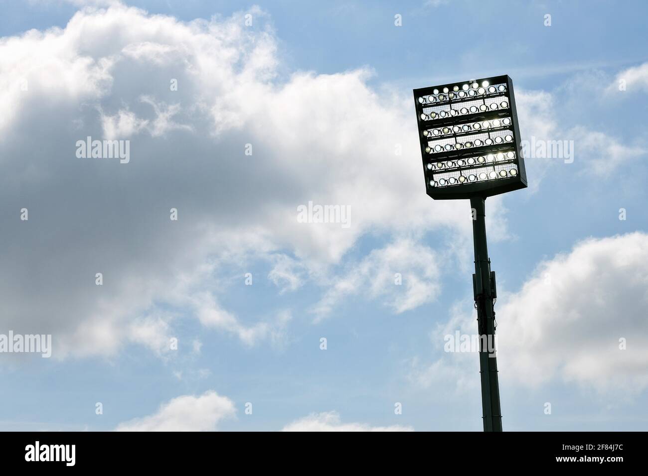 Flutlichtmast eingeschaltet vor blauem Himmel mit Wolken, Bochum, Deutschland Stockfoto