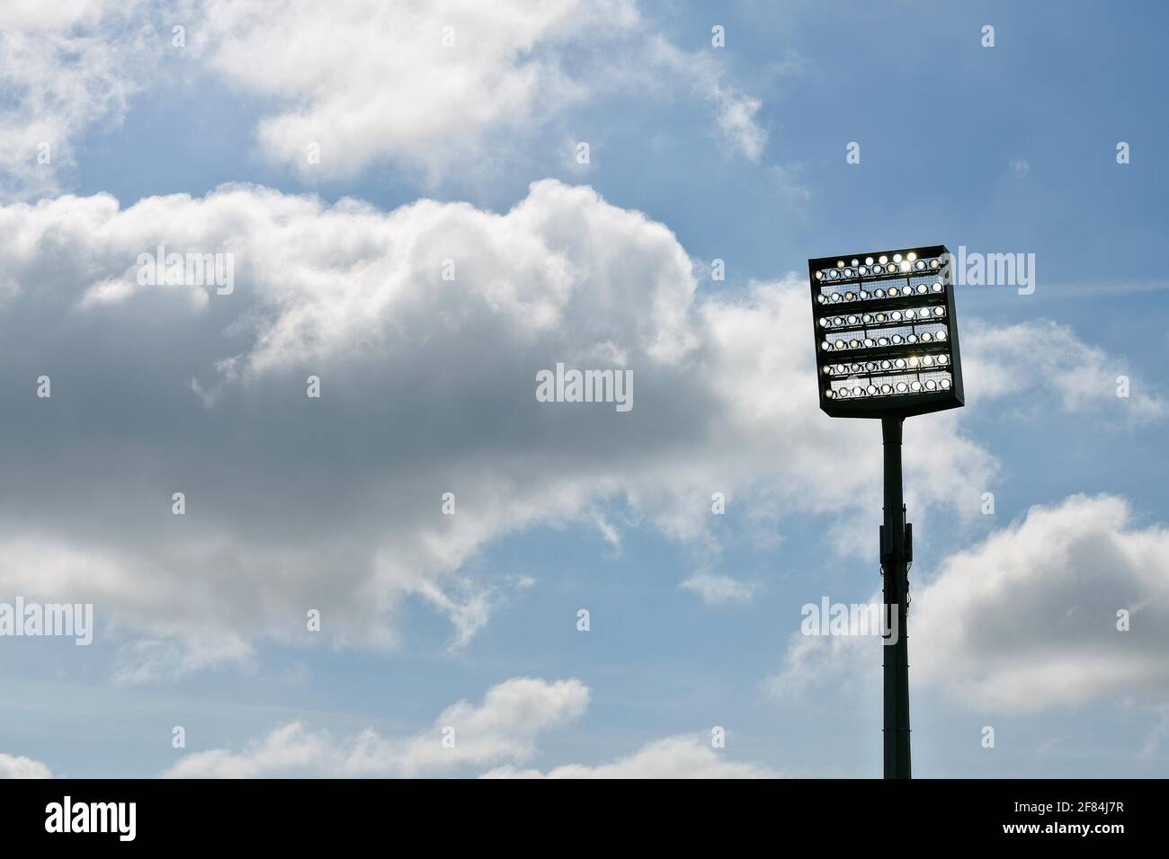 Flutlichtmast eingeschaltet vor blauem Himmel mit Wolken, Bochum, Deutschland Stockfoto