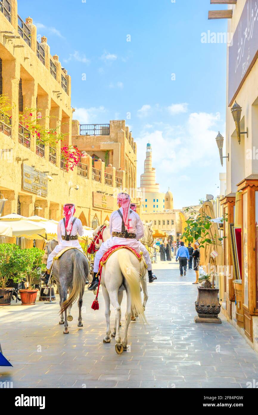 Doha, Katar - 20. Februar 2019: Heritage Police Officers in traditioneller katarischer Uniform auf dem alten Souq Waqif auf arabischen Pferden. Fanar Islamisch Stockfoto