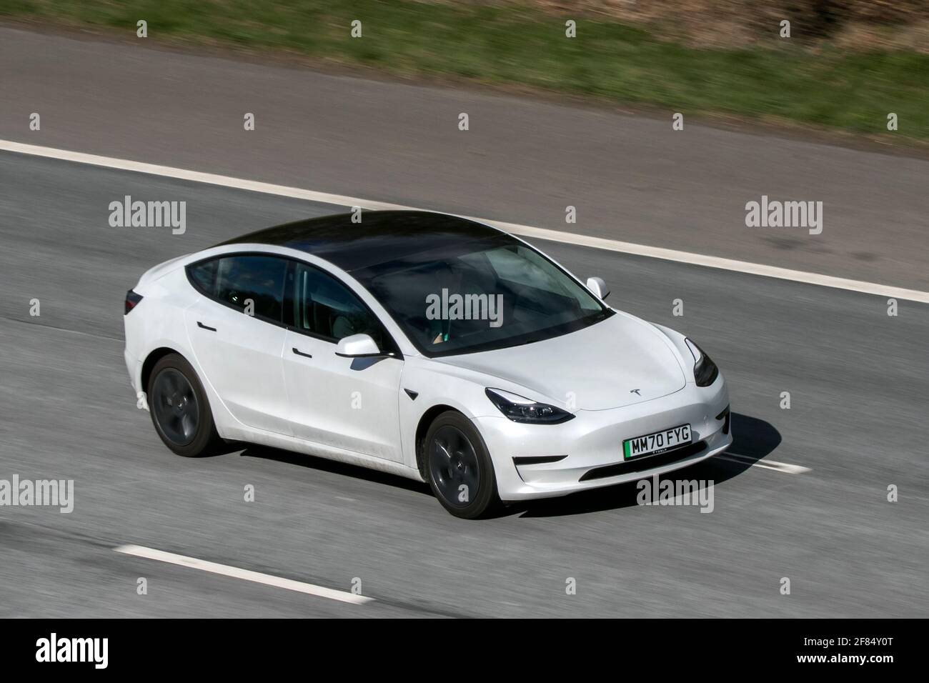2020 weißer Tesla Model 3 Standard Range + ;Fahren auf der Autobahn M6 in der Nähe von Preston in Lancashire, Großbritannien. Stockfoto