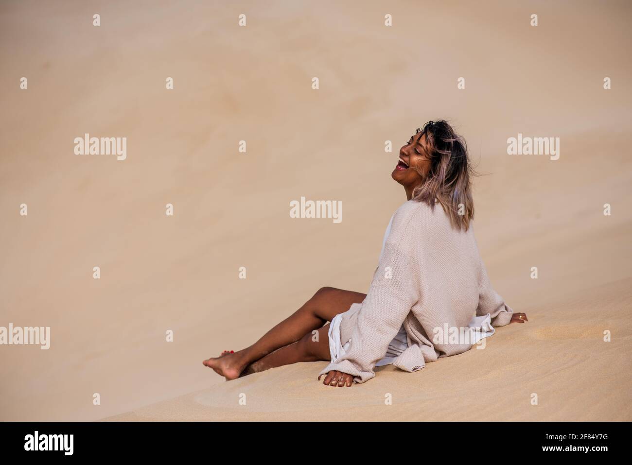 Glückliche Frau auf Sanddüne sitzen Stockfoto