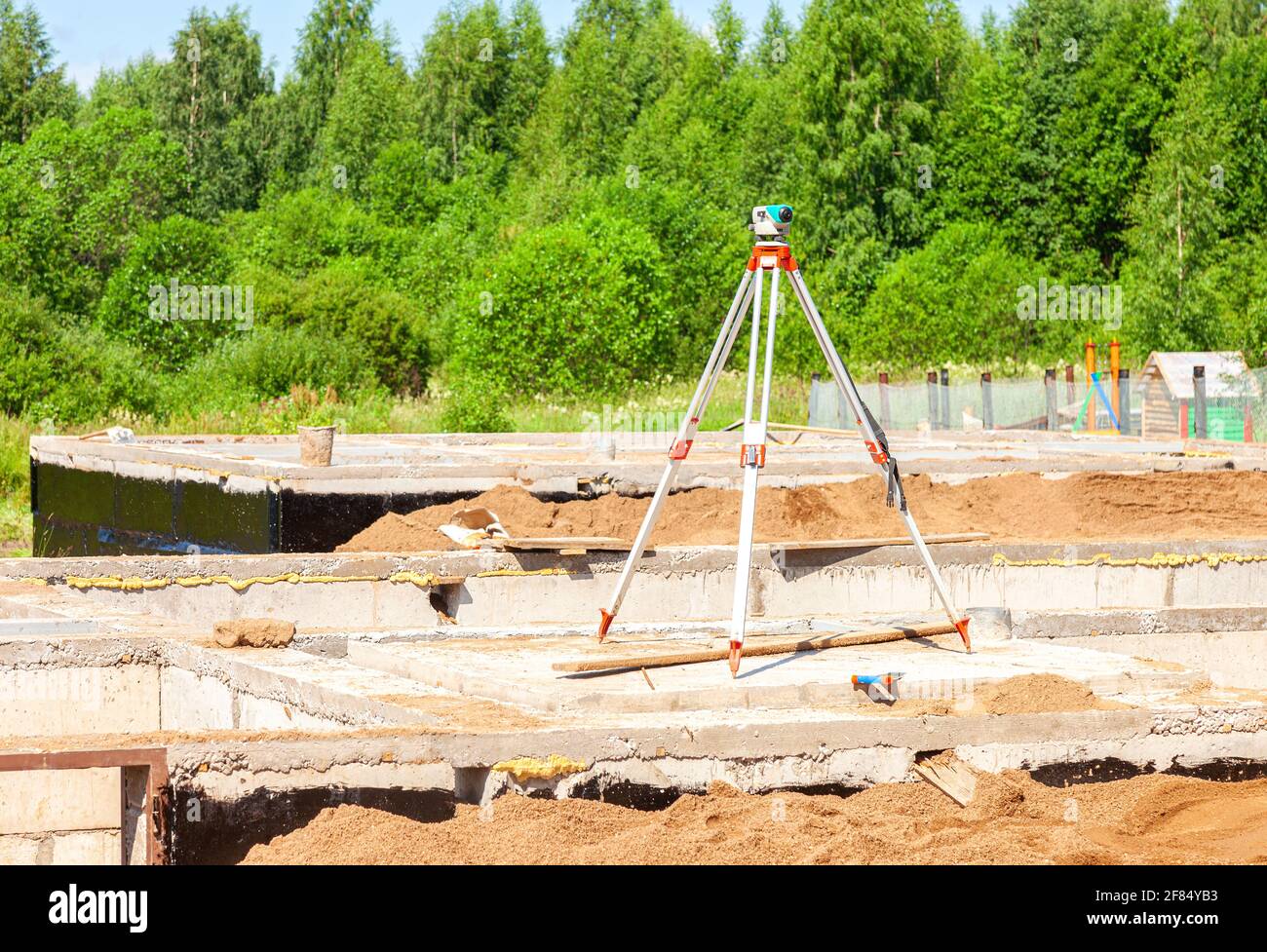 Geodätische Ausrüstung optische Ebene auf Stativ auf der Baustelle montiert. Vermesser sorgen für präzise Messungen Stockfoto