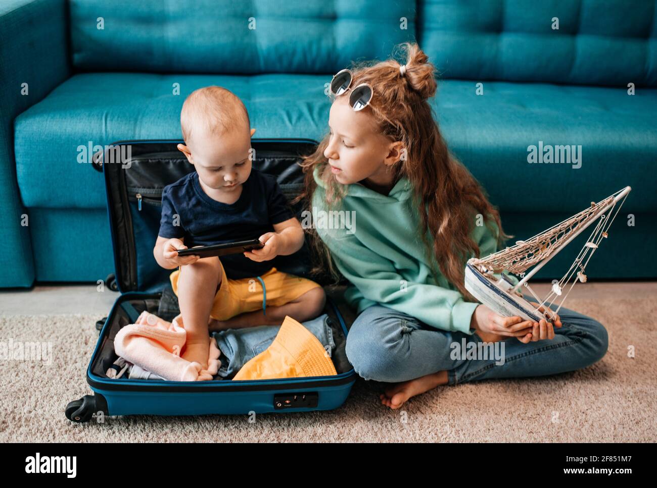 Glückliches Mädchen mit Reisekoffer zu Hause. Blaues Schiff, Urlaub auf dem Meer, Karte und Globus. Reisekonzept. Stockfoto