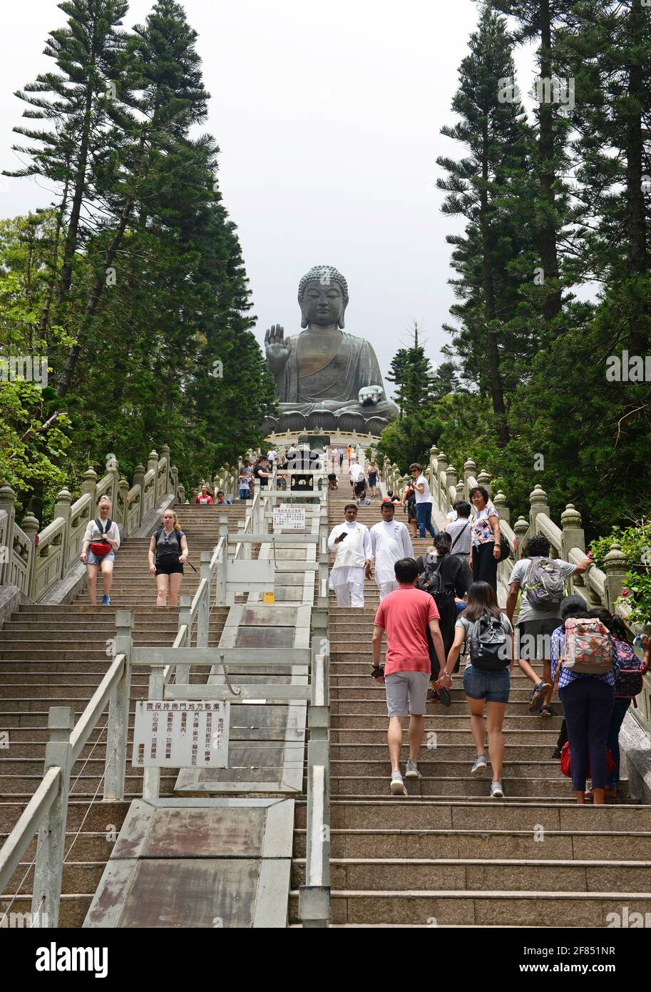 Der Tian Tan buddha wacht über die Besucher, die die Stufen von Ngongping auf der Insel Lantau, Hongkong, China, erklimmen Stockfoto