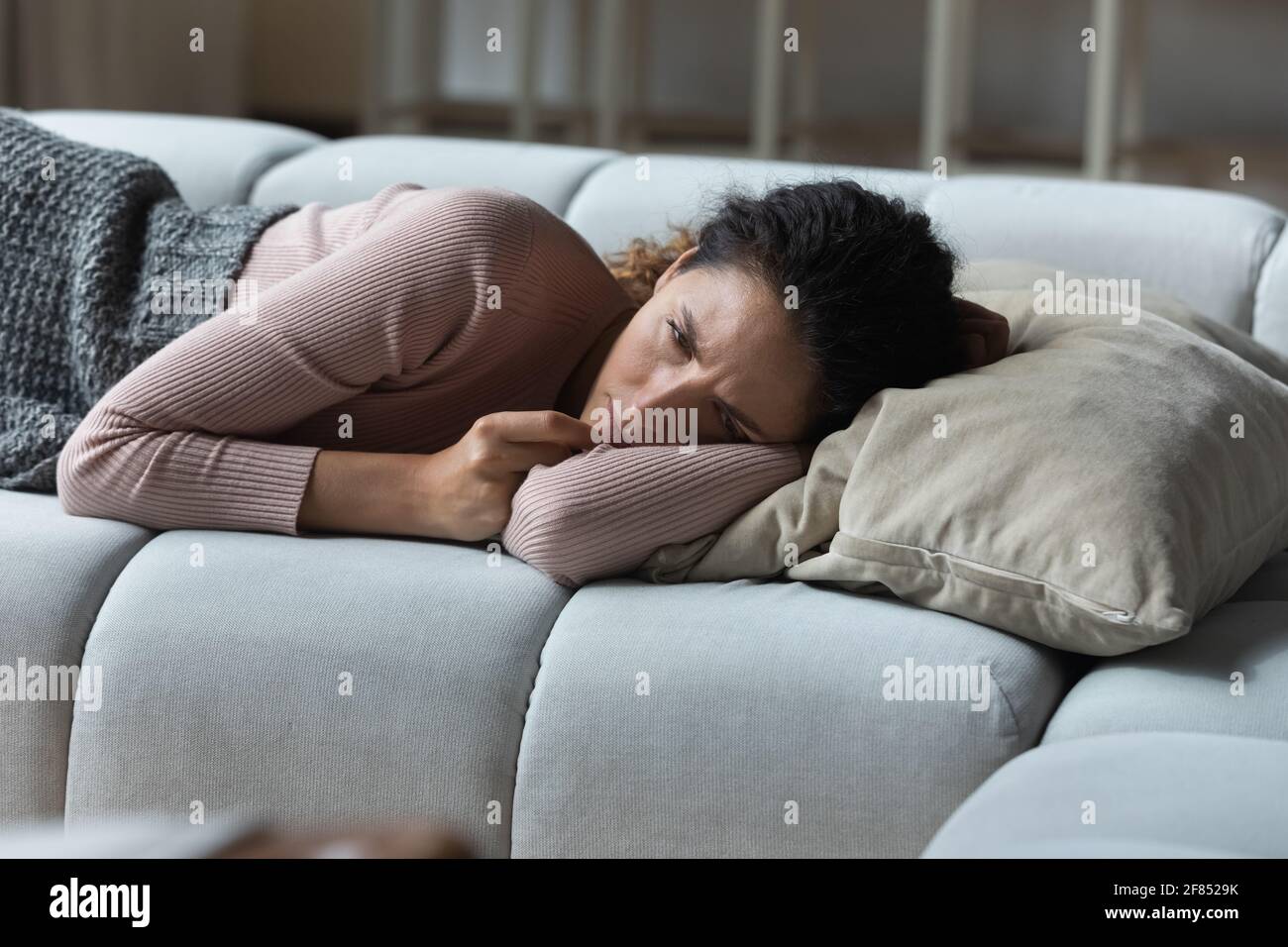 Gestresste traurige lateinerin, die auf dem Sofa liegt und nicht schlafen kann Stockfoto