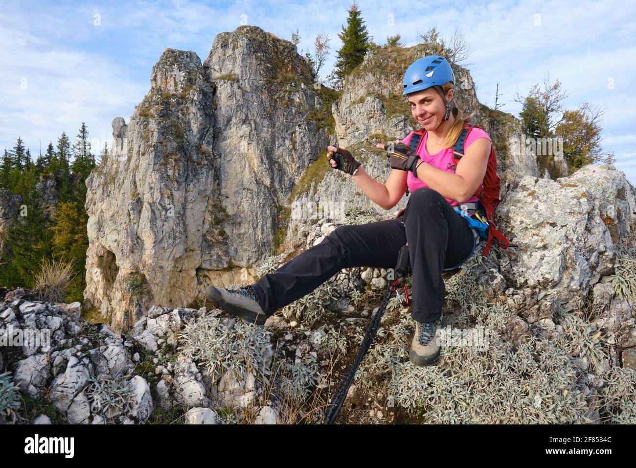 Die Frau weist auf einen Felsen auf einer Kletterroute, die sich auf einem Bergrücken namens Piatra Soimilor in Harghita County, Rumänien, befindet. Abenteuer, Tourismus, Sommer. Stockfoto