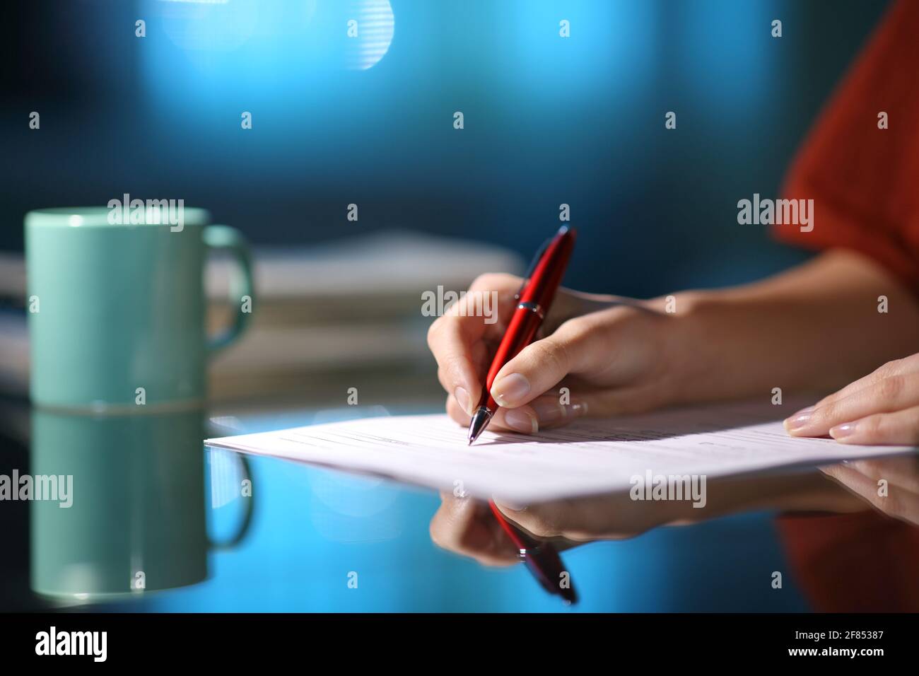 Nahaufnahme einer Frau, die das Papierformular ausfüllt In der Nacht zu Hause Stockfoto