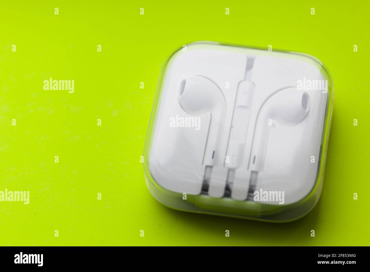 Wearable Tech / Lifestyle - Nahaufnahme eines Paares Kopfhörer mit Ohrhörer auf neongelbem Hintergrund Stockfoto