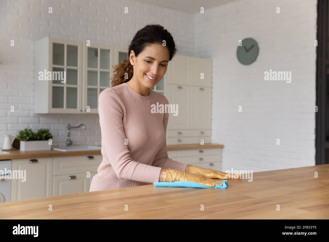 Glückliche tausendjährige latina Frau Hausfrau wischen Staub von der Küchentisch Stockfoto