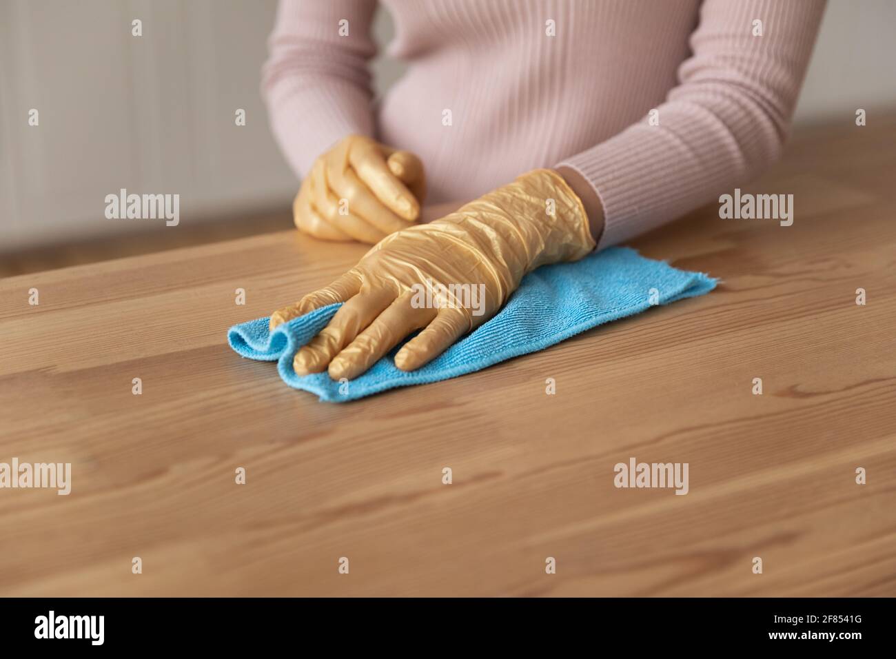 Junge weibliche Hände in Handschuhen mit Lappen, um Möbel zu stauben Stockfoto