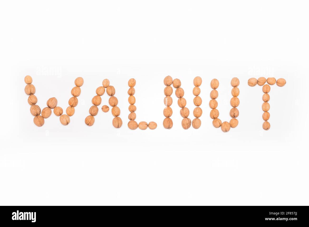 Wort Walnuss mit Walnüssen auf weißem Hintergrund ausgekleidet, isoliert. Stockfoto