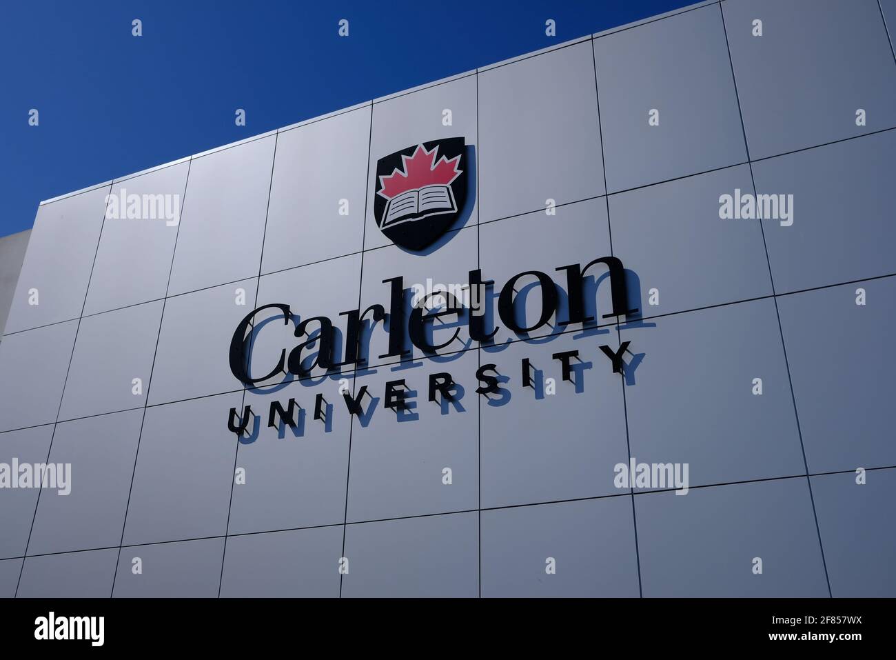 „Carleton University“ in großen Buchstaben und Logo an der Seite des glatten weißen Gebäudes des Parkplatzes P7 am Eingang des Campus. Ottawa, Ontario, Kanada. Stockfoto
