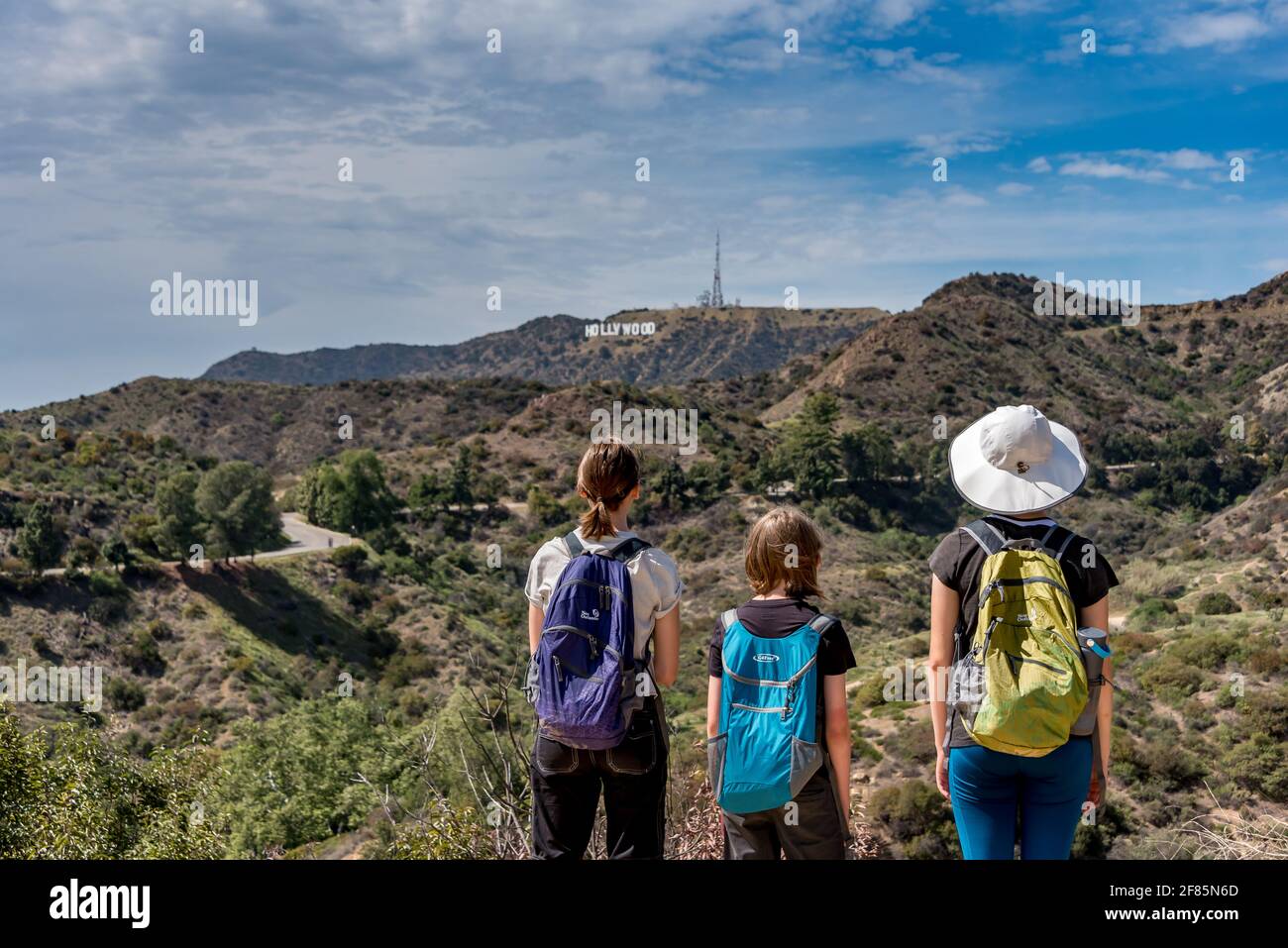 Drei Kinder blicken von einem Wanderweg im Griffith Park, Los Angeles, Kalifornien, auf das Hollywood-Schild, während sie in einem Familienurlaub wandern. Stockfoto