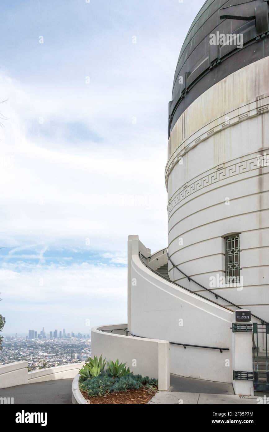 Architektonisches Detail der Außenseite des Griffith Observatoriums mit Downtown Los Angeles in der Ferne, gebogene Treppe und Kuppel. Stockfoto