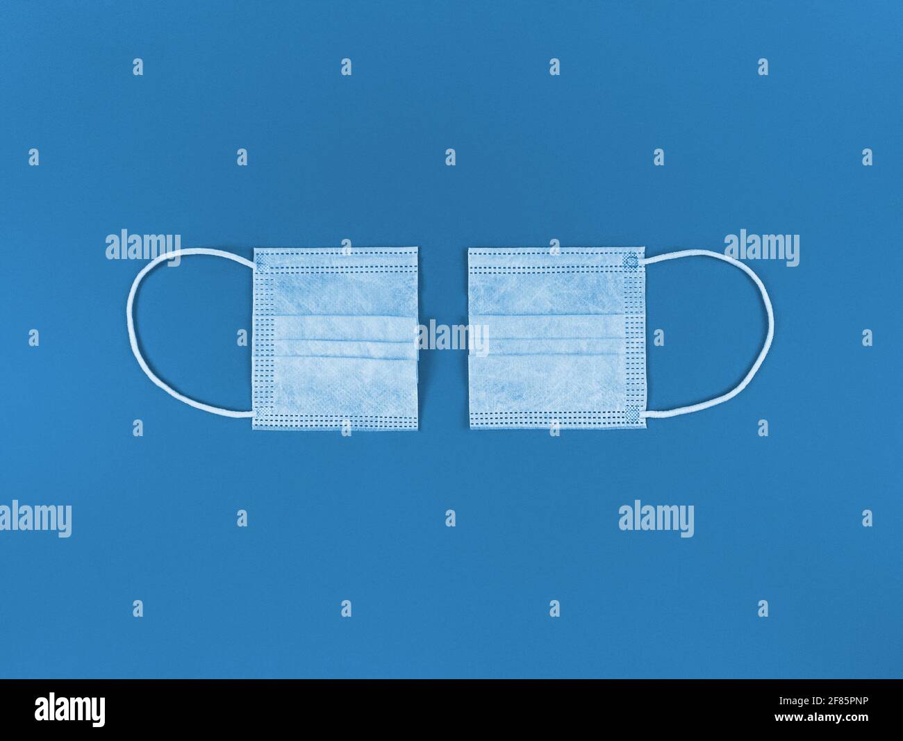 Medizinische Einweg-Gesichtsmaske in zwei Hälften auf einem blauen Hintergrund geschnitten. Stockfoto