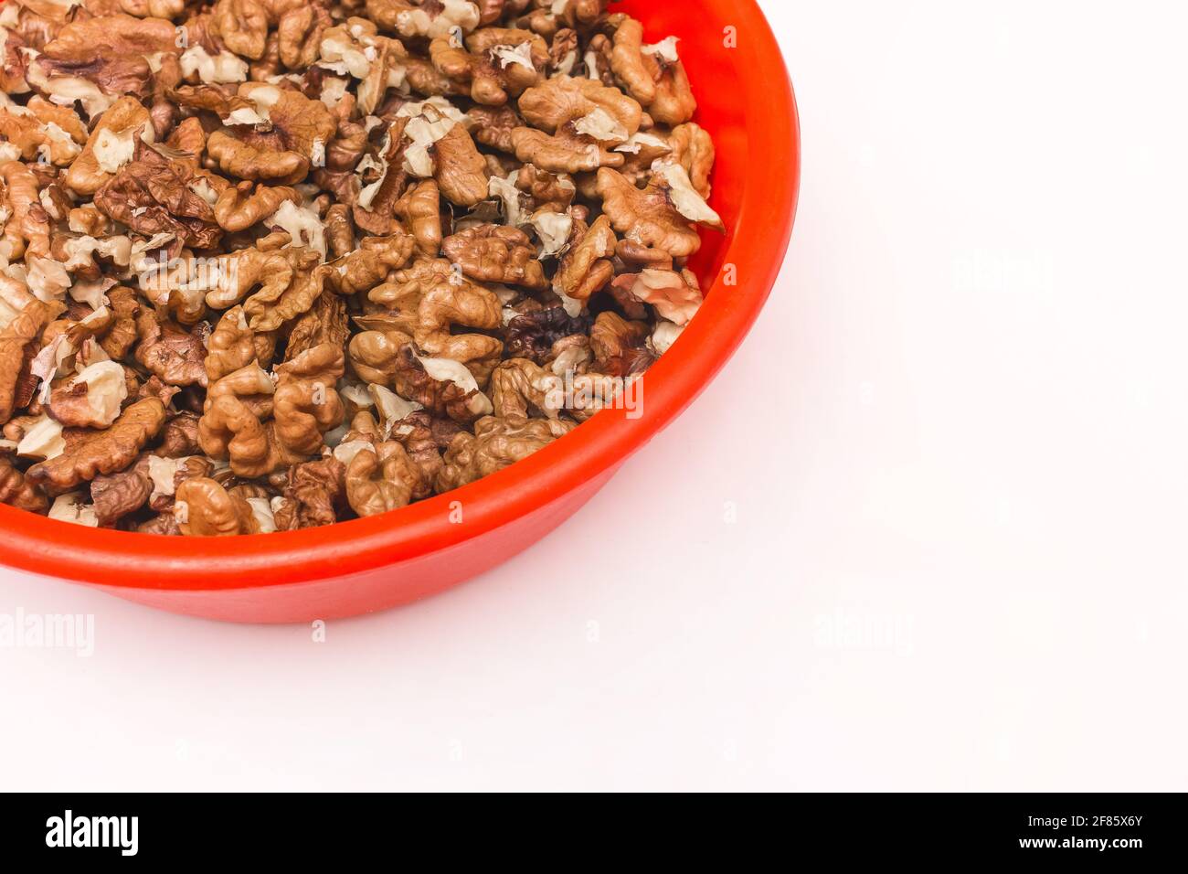 Geschälte Walnüsse in roter Kunststoffplatte auf weißem Hintergrund, isoliert. Stockfoto