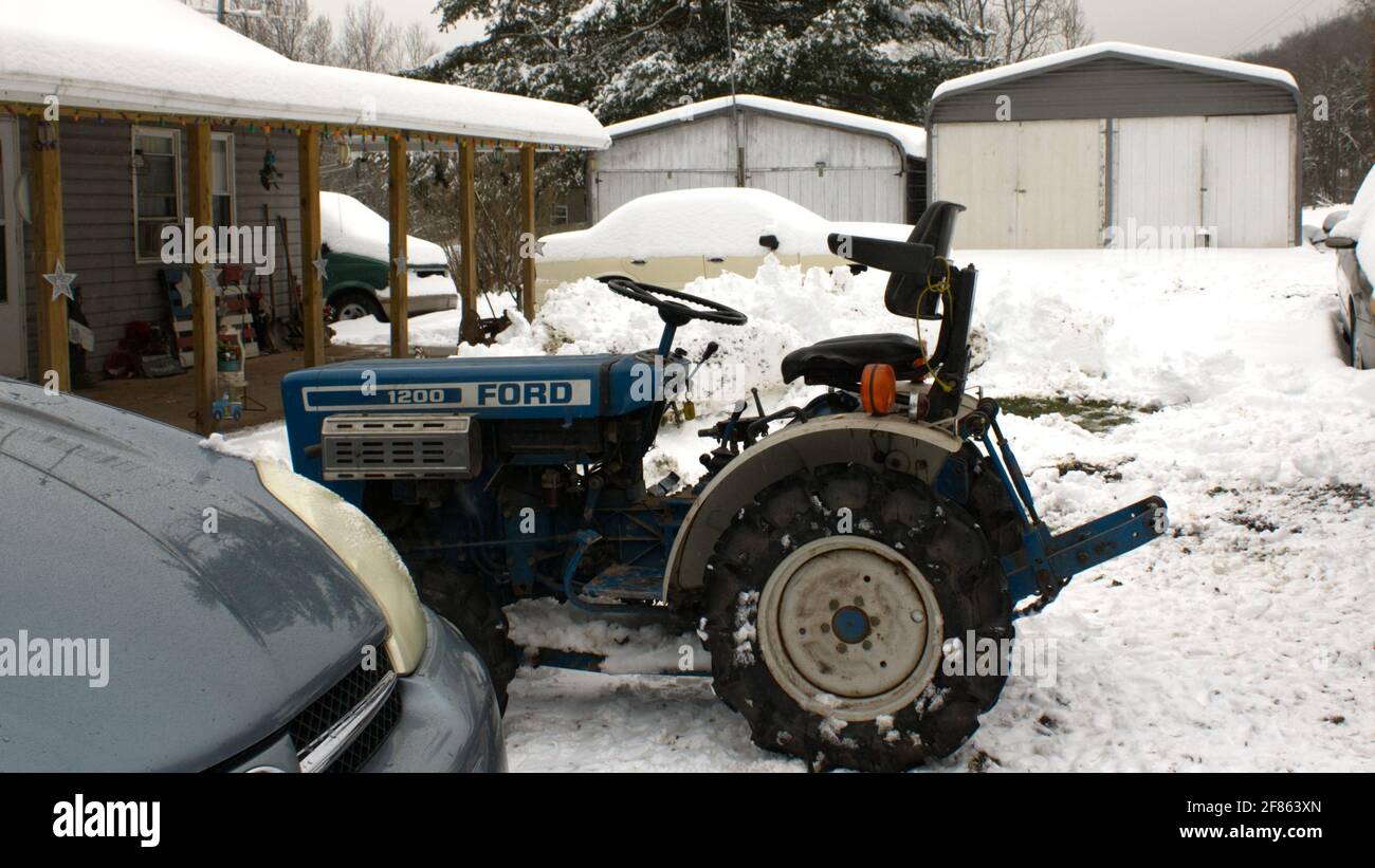 Ein alter Ford Kompakttraktor bei der Arbeit im Schnee Stockfoto