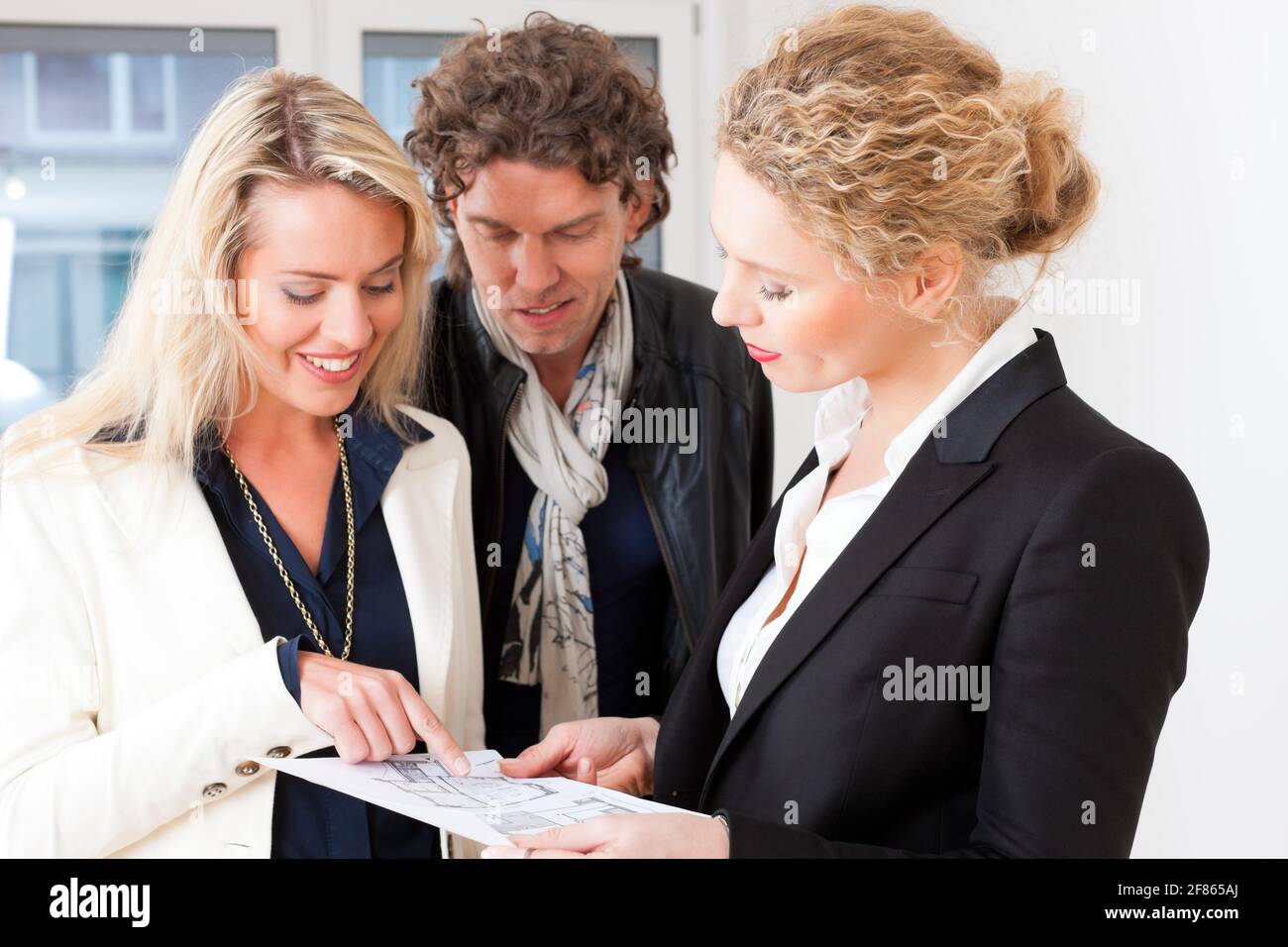 Junge Makler erklären Grundriss mit paar in einer Wohnung Stockfoto