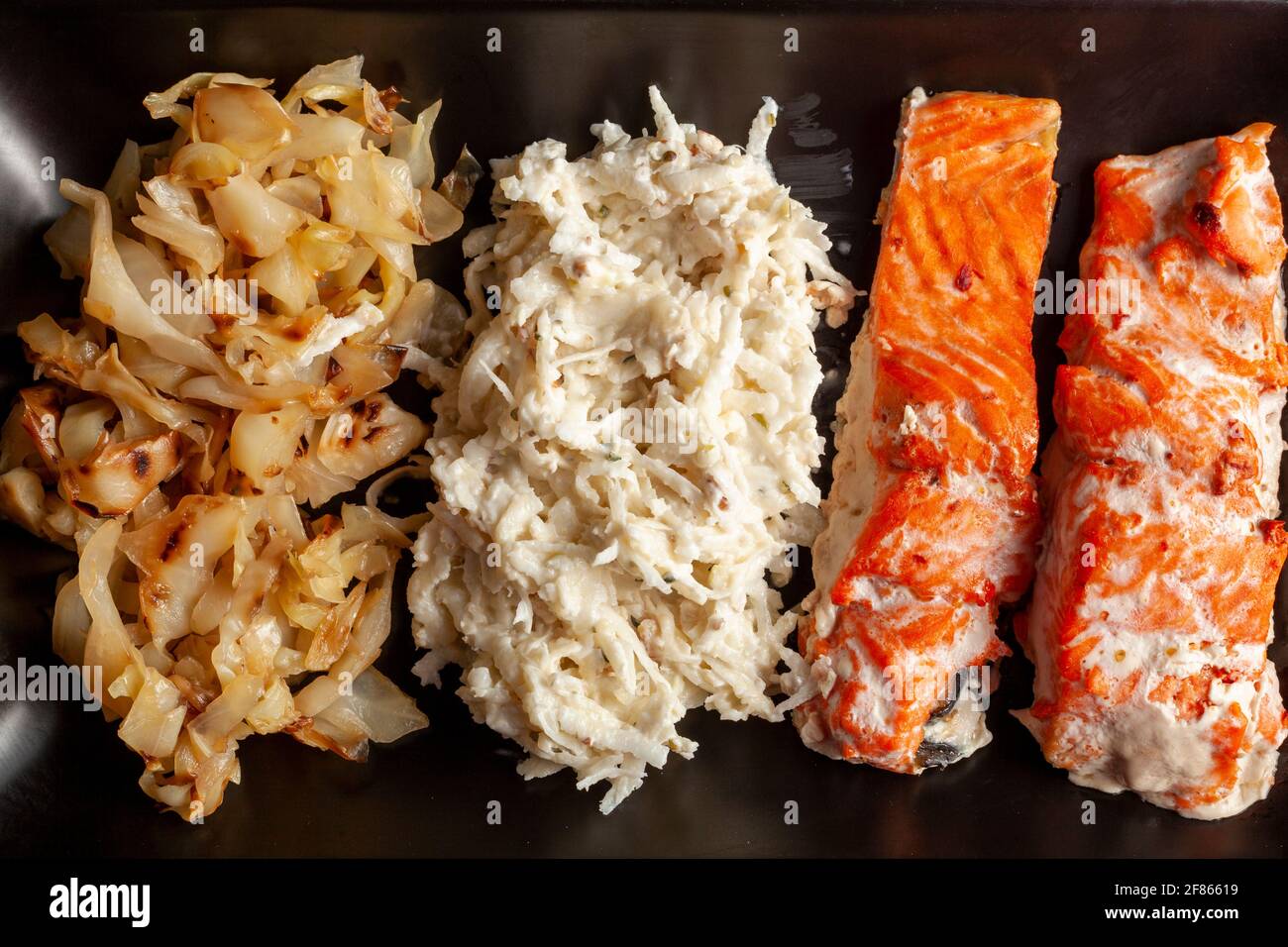 Eine Portion im Ofen gekochter marinierter Lachsfilets mit Kohl und Sellerie-Salaten, um den Ballaststoff- und Vitamingehalt zu erhöhen. Eine gesunde, ausgewogene Ernährung concep Stockfoto