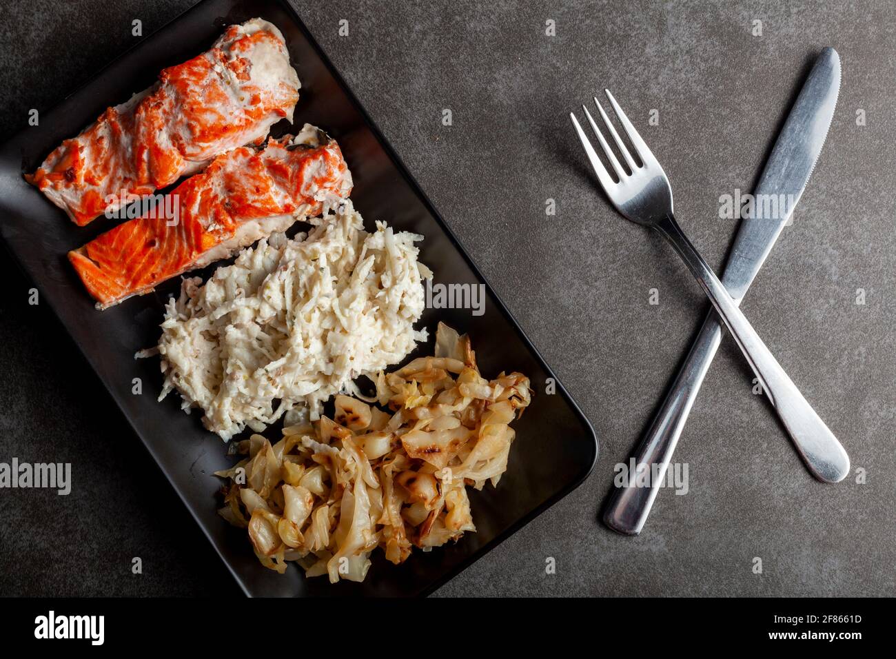 Eine Portion im Ofen gekochter marinierter Lachsfilets mit Kohl und Sellerie-Salaten, um den Ballaststoff- und Vitamingehalt zu erhöhen. Eine gesunde, ausgewogene Ernährung concep Stockfoto