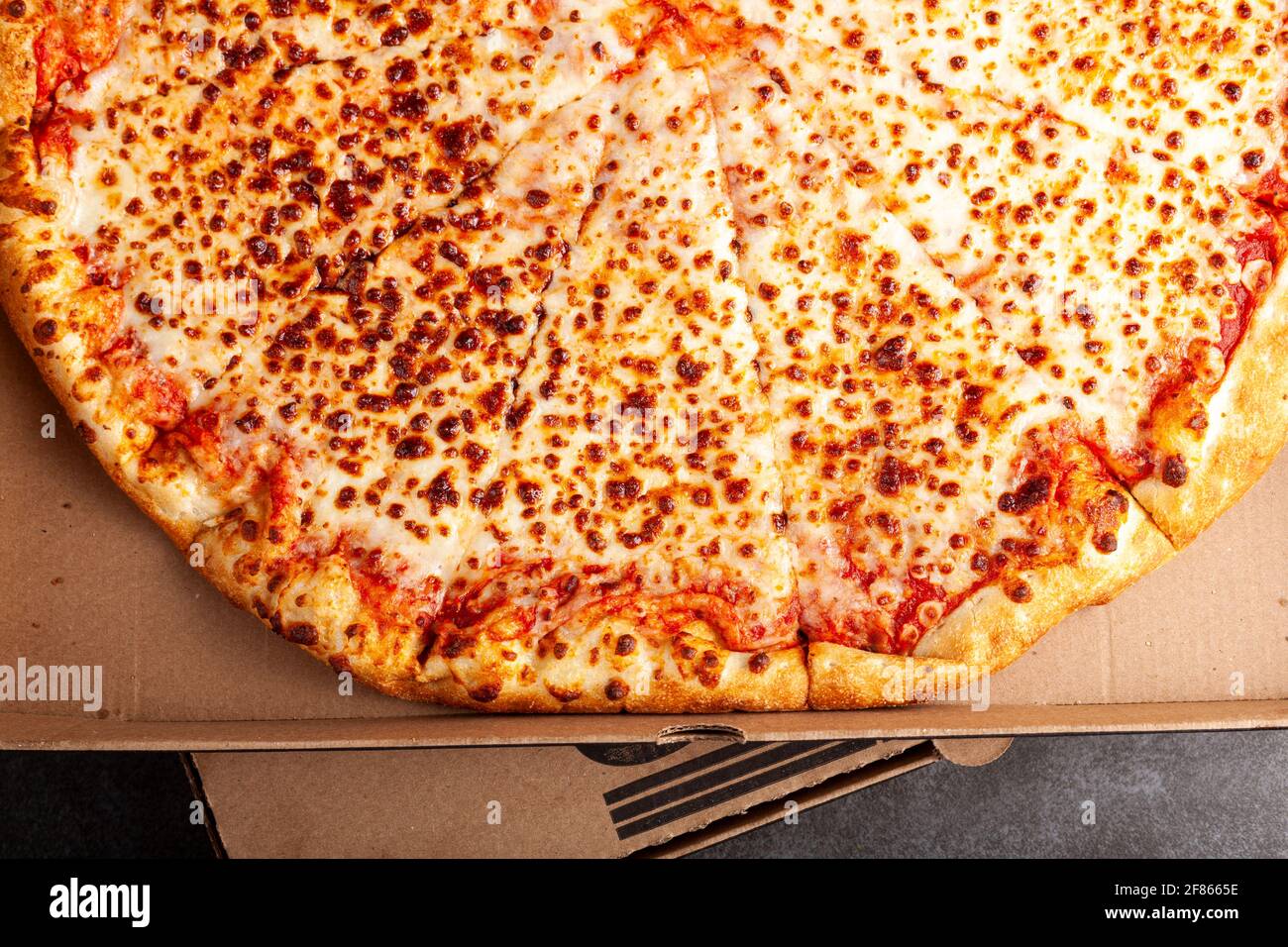 Flaches Bild eines frisch gebackenen Ladens, der in Scheiben geschnittene Pizza mit vier Käsesorten in einer Pizzakarton aus Pappe gekauft hat. Es hat reiche Belag und bietet einen leckeren Snack. Schnell foo Stockfoto