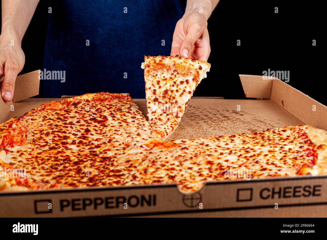Nahaufnahme des oberen Bildes einer kaukasischen Frau, die im Hintergrund eine Scheibe Frischkäse-Pizza mit einer großen Pizza in einer Kartonbox hält. Konzeptbild für fast Stockfoto