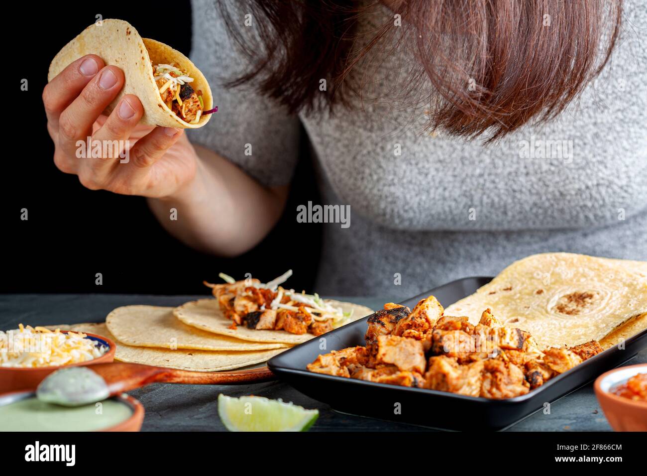 Nahaufnahme eines mexikanischen Taco-Tellers mit Maistortillas, vorgekochten Hühnerstücken, Kohlschlaw, geschreddertem Käse, Salsa und Rahmsoße Stockfoto