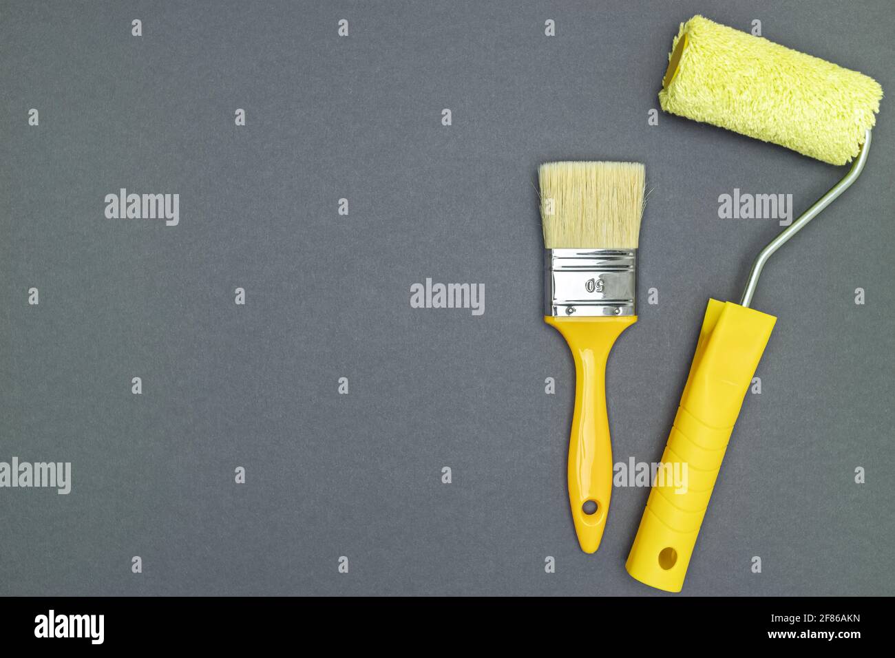 Malwerkzeuge für Hausrenovierungen - Pinsel und Farbe Rolle auf grauem Hintergrund Stockfoto