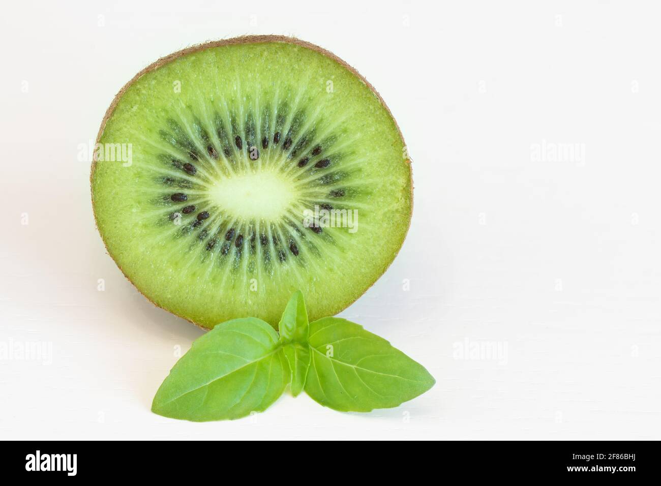 Halbe Kiwi-Frucht mit isoliertem Blatt auf weißem Hintergrund Stockfoto