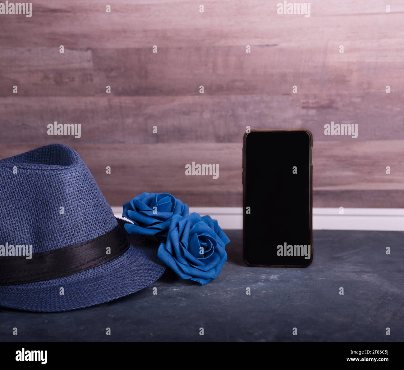 Herren Accessoire Geschenk zum Vatertag oder Jubiläum auf Holztisch Hintergrund, blaue Rosen, Hut und Handy. Text für Leerzeichen kopieren. Stockfoto