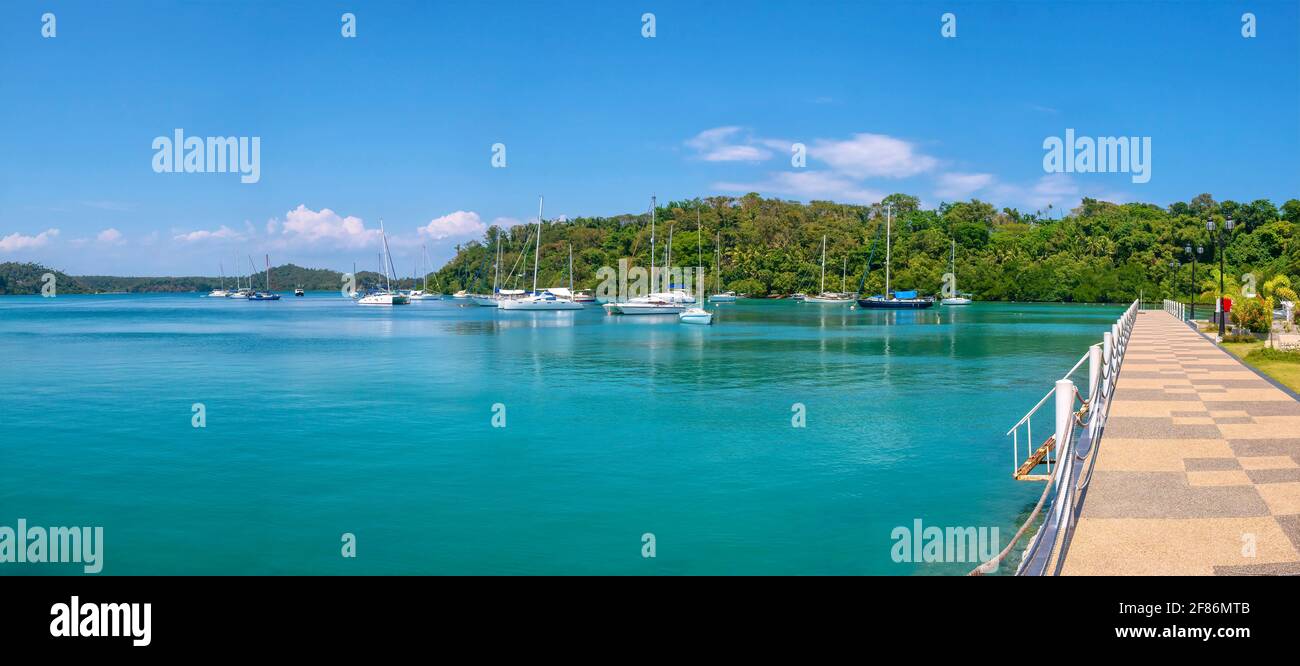 Panoramablick auf die schöne Muelle Bay im Ferienort Puerto Galera, Philippinen, mit Freizeitjachten, die in ruhigem türkisfarbenem Wasser vertäut sind. Stockfoto Panoramablick auf die schöne Muelle Bay im Ferienort Puerto Galera, Philippinen, mit Freizeitjachten, die in ruhigem türkisfarbenem Wasser vertäut sind. Stockfoto