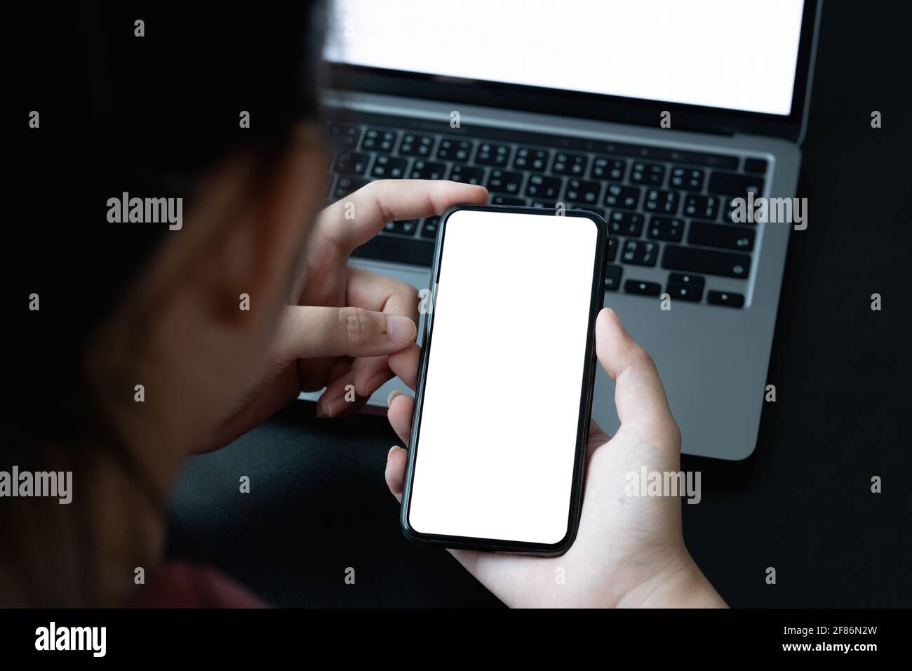 Draufsicht der Geschäftsfrau mit Smartphone auf Workplcae mit leerem weißen Bildschirm. Modell Handy. Stockfoto