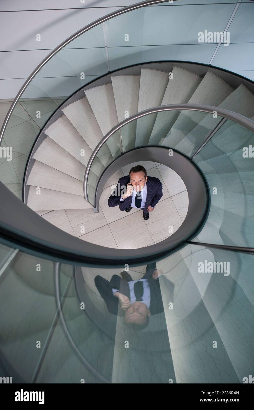 Portrait Geschäftsmann im Gespräch auf Smartphone unter Wendeltreppe Stockfoto