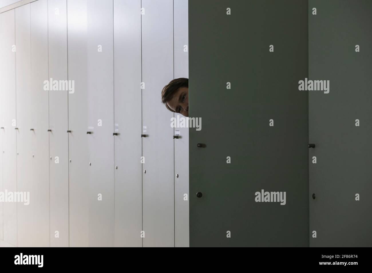 Portrait verspielter Geschäftsmann, der aus dem Schließfach guckend hereinspätet Stockfoto