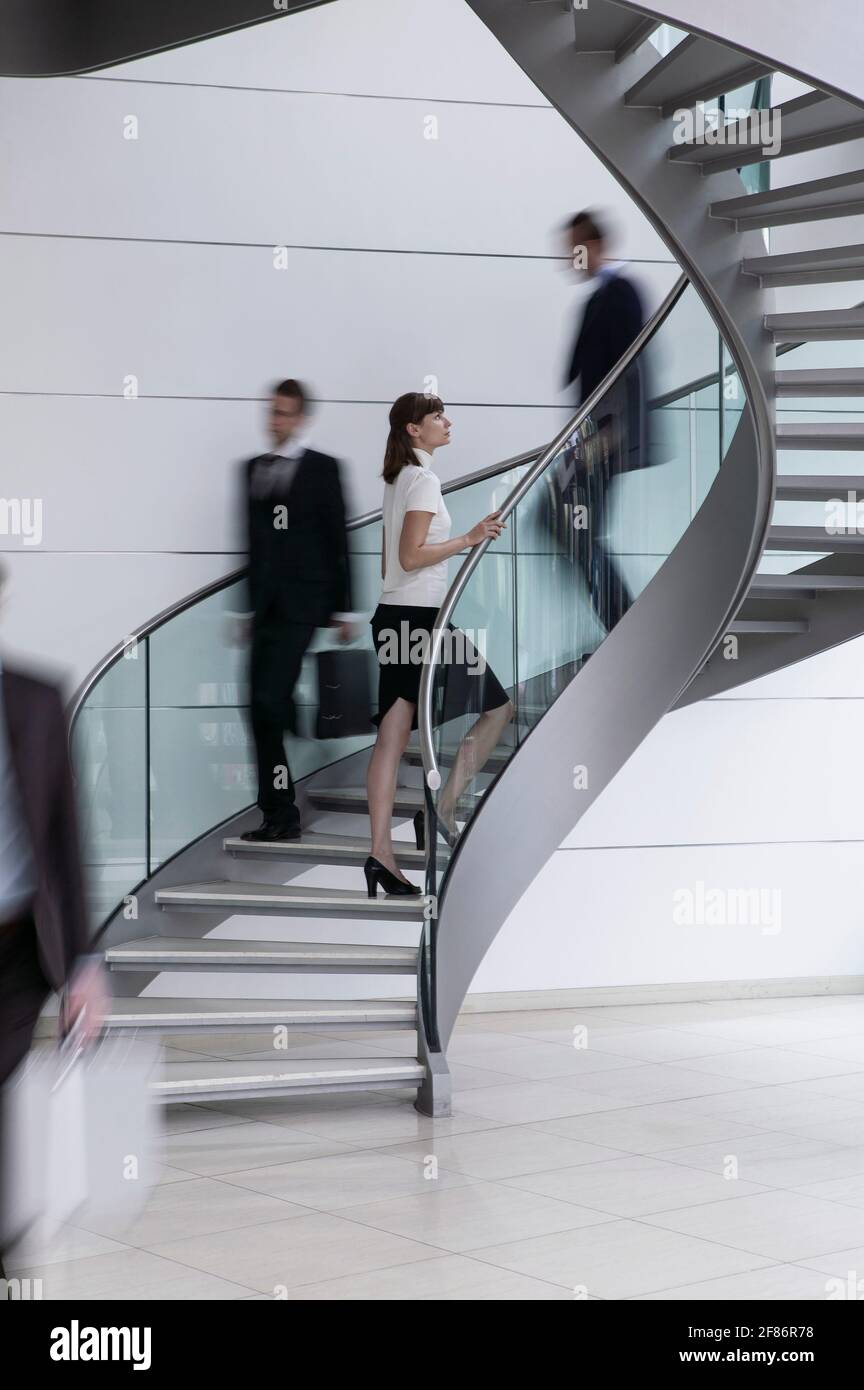 Junge Geschäftsfrau steigt Wendeltreppe im Büro Stockfoto