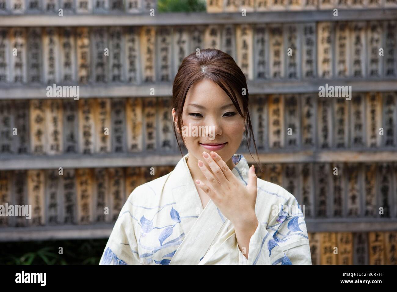 Schöne junge Frau im Kimono an japanischen Gebetstafeln Stockfoto